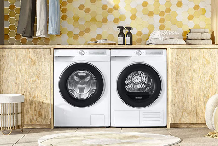 Pralka i suszarka umieszczone obok siebie w nowoczesnej łazience z drewnianymi akcentami.